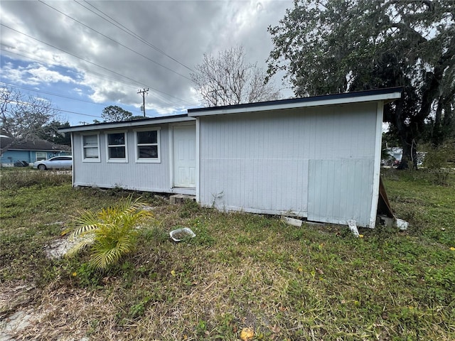 rear view of property with an outbuilding and a yard