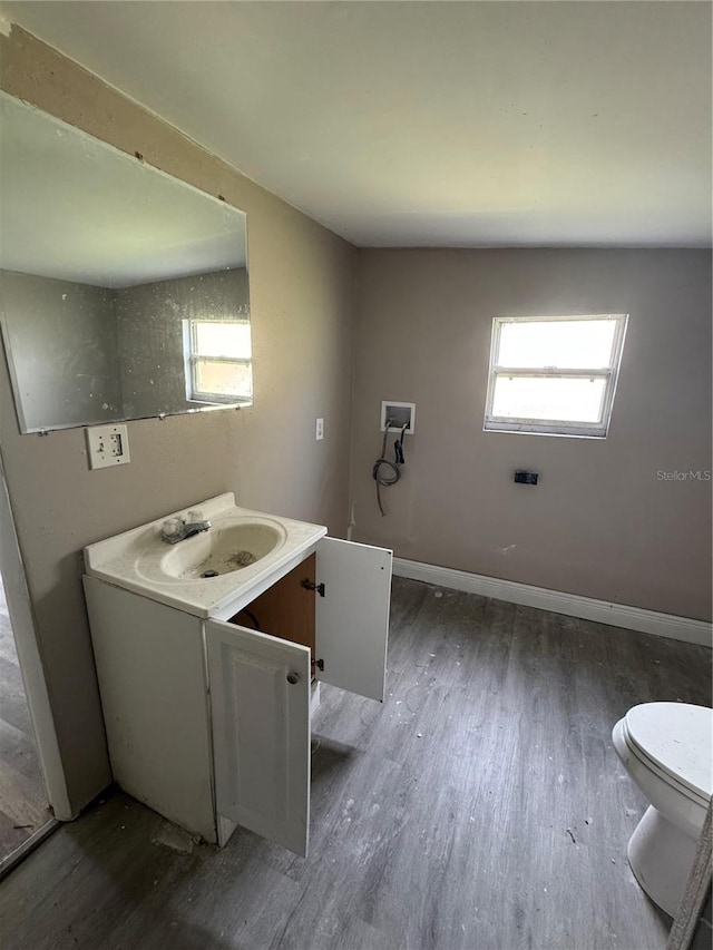 bathroom with toilet, vanity, baseboards, and wood finished floors