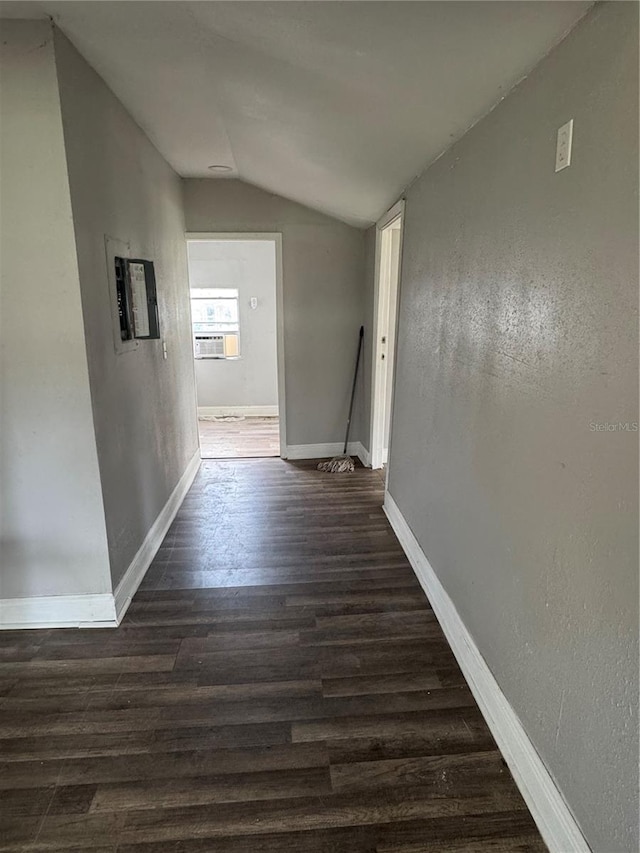 corridor with dark wood-style floors, baseboards, and lofted ceiling