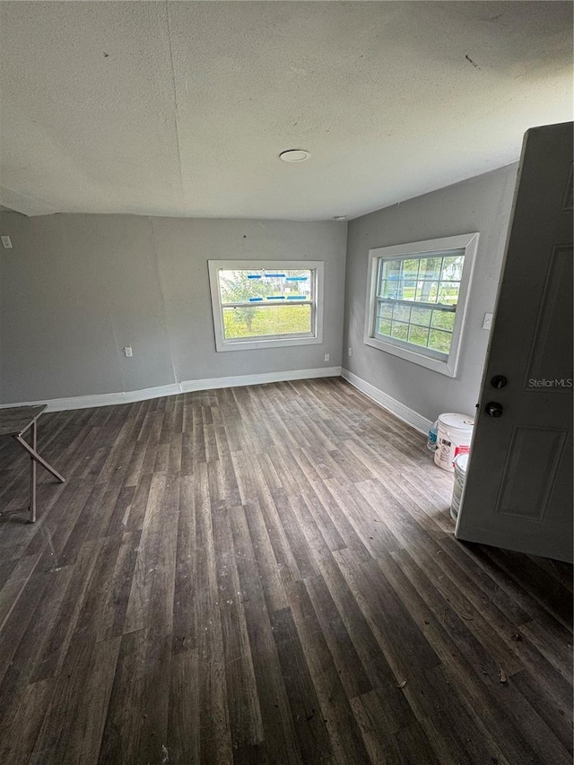 unfurnished living room featuring baseboards, a textured ceiling, and wood finished floors