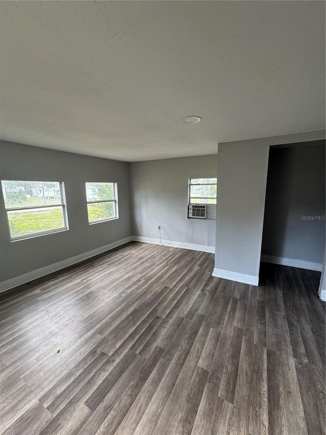 empty room with baseboards, a textured ceiling, and dark wood-style floors