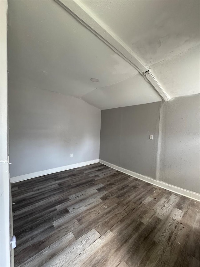 empty room with vaulted ceiling, baseboards, and dark wood-style flooring