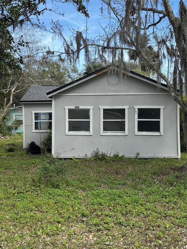 view of side of property featuring a yard and roof with shingles