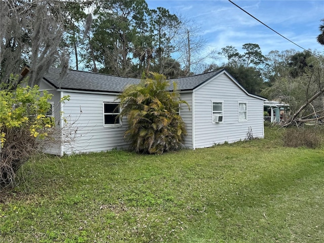 exterior space with cooling unit, a yard, and roof with shingles