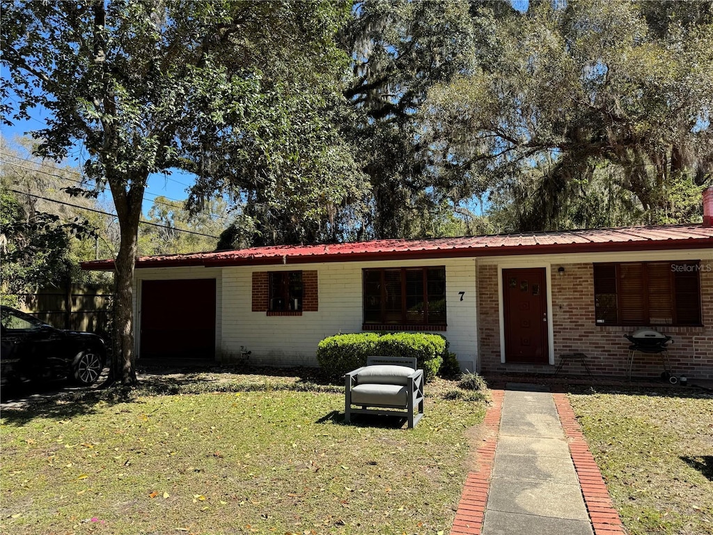 single story home with brick siding, metal roof, and a front yard