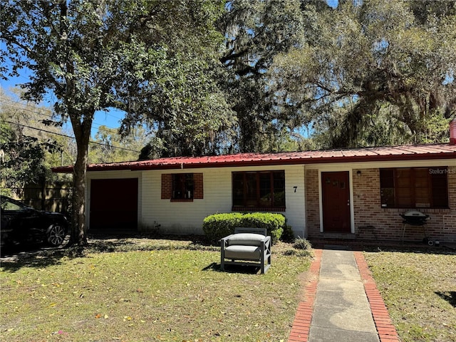 single story home with brick siding, metal roof, and a front yard