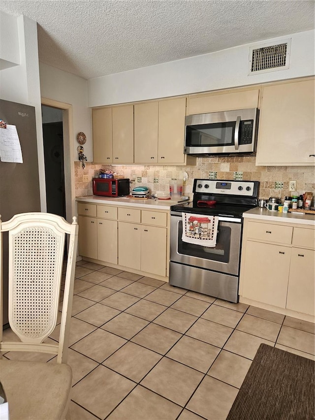 8744 54th Ave W Unit 8744, Bradenton, FL 34210 - kitchen featuring appliances with stainless steel finishes, cream cabinets, light countertops, a textured ceiling, and decorative backsplash