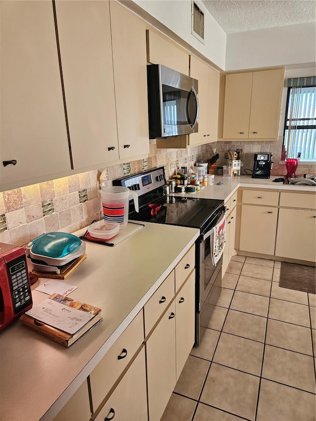 8744 54th Ave W Unit 8744, Bradenton, FL 34210 - kitchen featuring appliances with stainless steel finishes, cream cabinetry, light countertops, backsplash, and light tile patterned floors