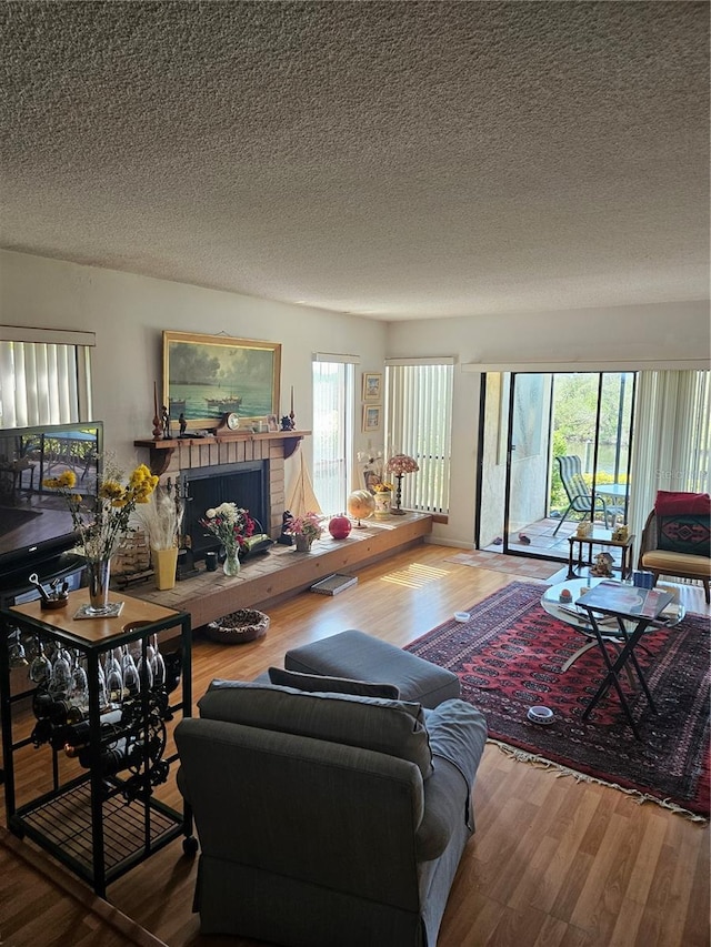 8744 54th Ave W Unit 8744, Bradenton, FL 34210 - living room featuring wood finished floors, plenty of natural light, a fireplace, and a textured ceiling