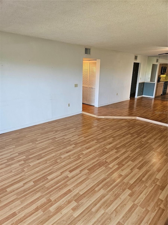 8744 54th Ave W Unit 8744, Bradenton, FL 34210 - spare room featuring light wood-style flooring, a textured ceiling, and baseboards