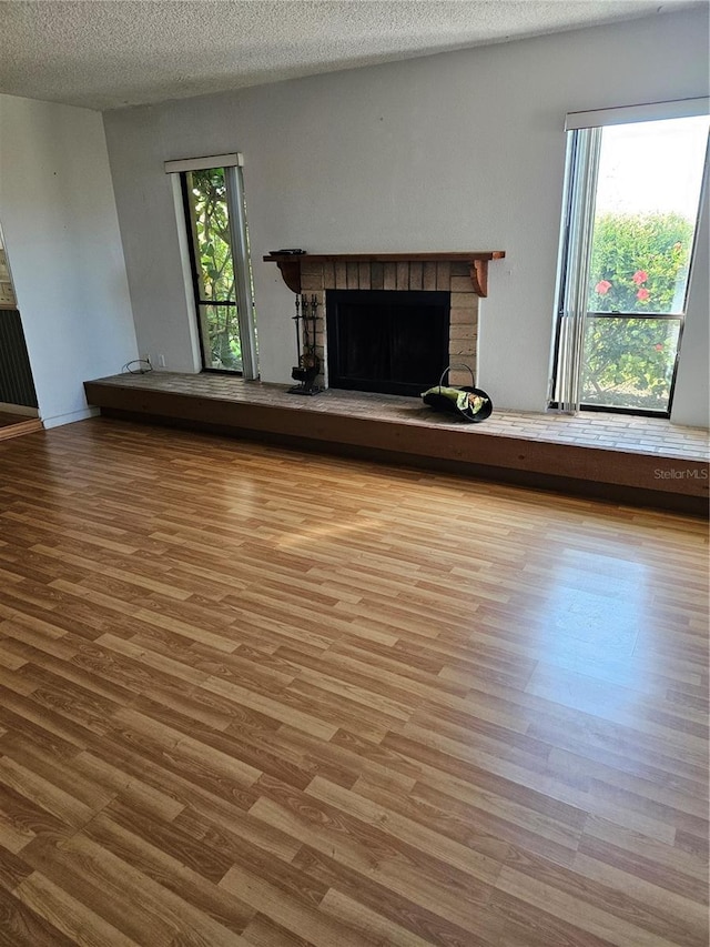 8744 54th Ave W Unit 8744, Bradenton, FL 34210 - unfurnished living room with a fireplace, wood finished floors, and a textured ceiling