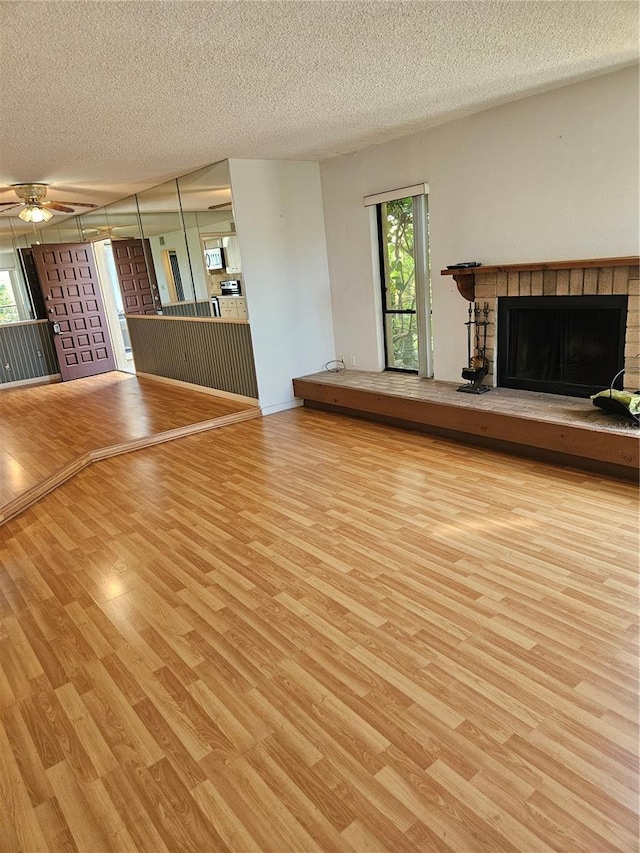 8744 54th Ave W Unit 8744, Bradenton, FL 34210 - unfurnished living room featuring wood finished floors, a textured ceiling, a fireplace, and ceiling fan