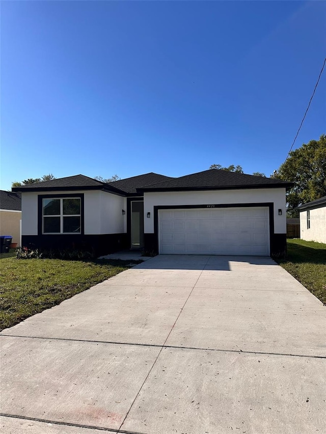 view of front of property with concrete driveway, a garage, a front yard, and stucco siding