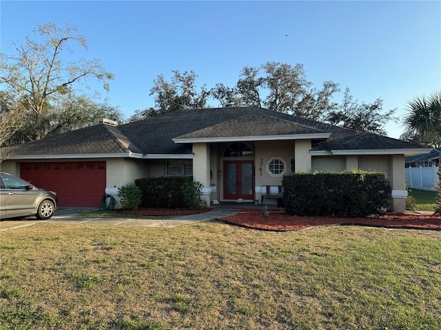 ranch-style house with french doors, an attached garage, a front yard, and stucco siding