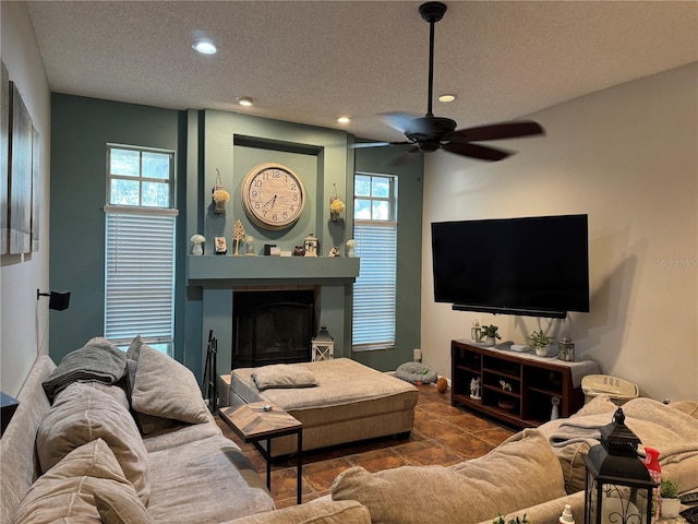 living area with a large fireplace, recessed lighting, a ceiling fan, and a textured ceiling