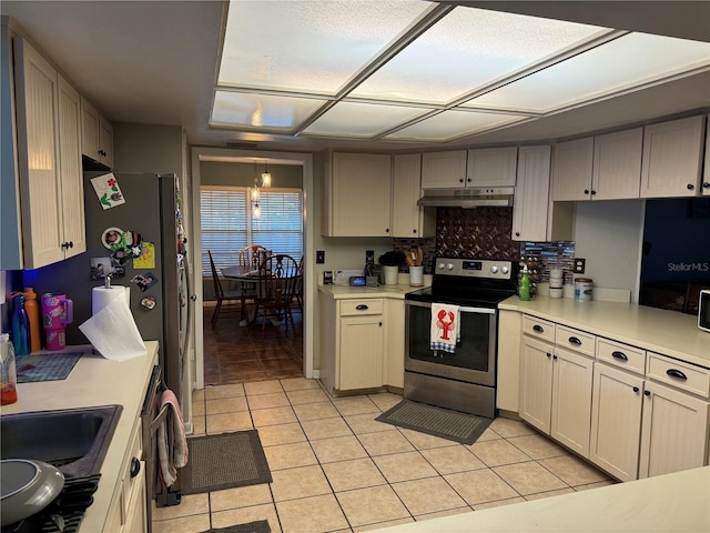 kitchen featuring under cabinet range hood, light countertops, light tile patterned floors, decorative backsplash, and electric range