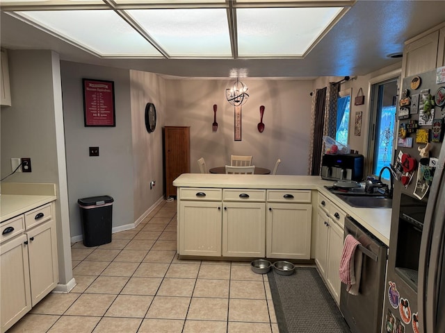 kitchen featuring a sink, appliances with stainless steel finishes, a peninsula, light countertops, and light tile patterned floors