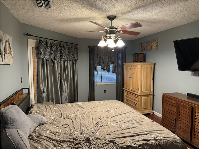 bedroom with visible vents, a textured ceiling, ceiling fan, and dark wood-style flooring