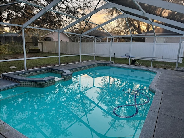 view of pool featuring glass enclosure, a yard, a pool with connected hot tub, and fence