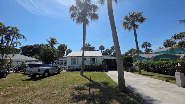 view of front facade featuring concrete driveway, a front yard, and metal roof