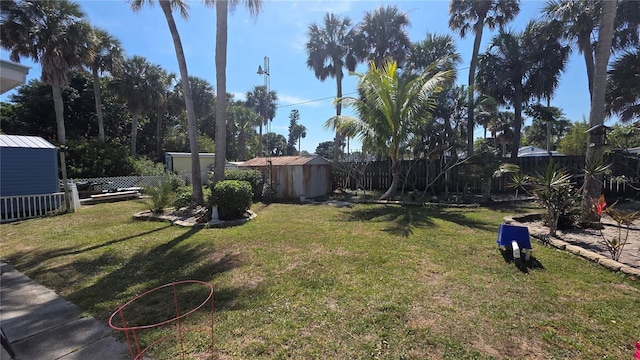 view of yard with a storage shed, a fenced backyard, and an outbuilding