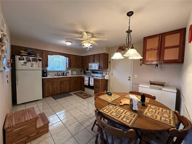 kitchen with light countertops, a ceiling fan, a sink, white appliances, and hanging light fixtures