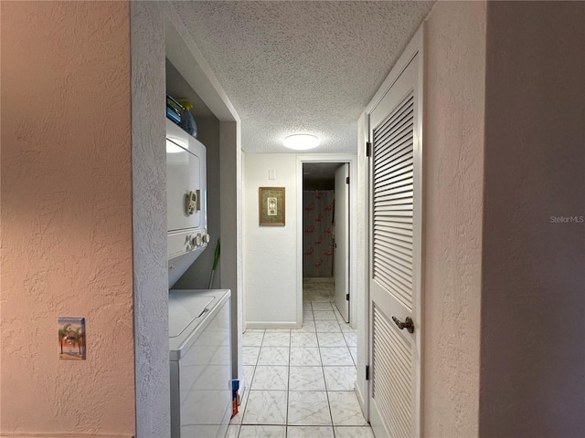 interior space with stacked washer / drying machine, a textured wall, marble finish floor, and a textured ceiling