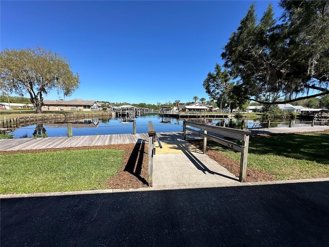 view of dock with a water view and a yard