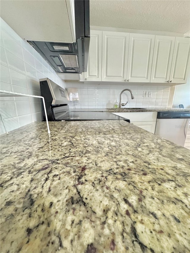 kitchen featuring stainless steel appliances, tasteful backsplash, white cabinetry, a sink, and light stone counters