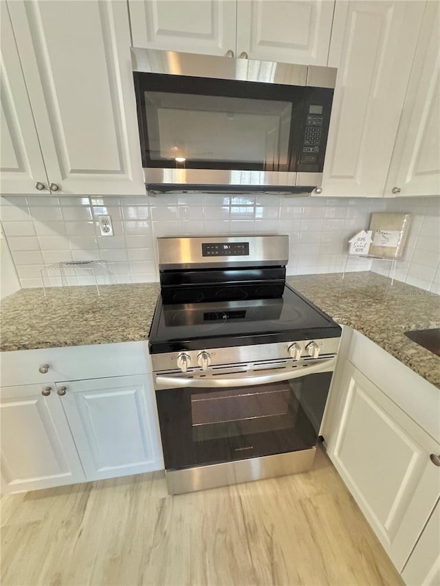 kitchen with white cabinets, light stone counters, tasteful backsplash, and appliances with stainless steel finishes