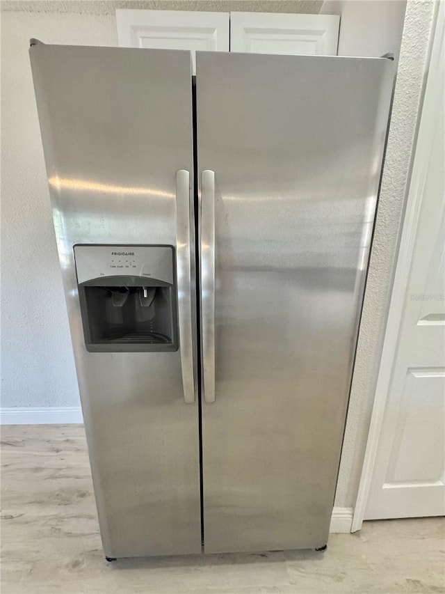 details with baseboards, light wood-type flooring, white cabinets, and stainless steel refrigerator with ice dispenser