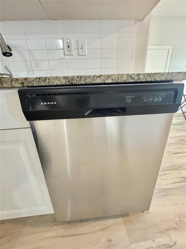 interior details featuring dishwasher, light wood-style flooring, light stone countertops, and decorative backsplash