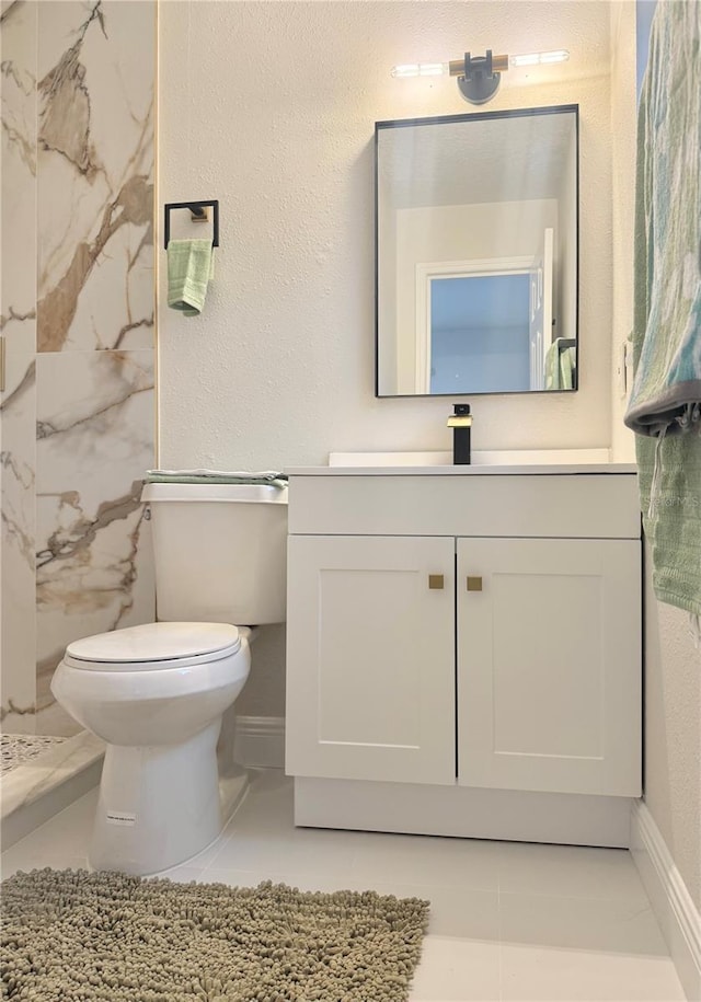 bathroom with baseboards, a textured wall, toilet, and vanity