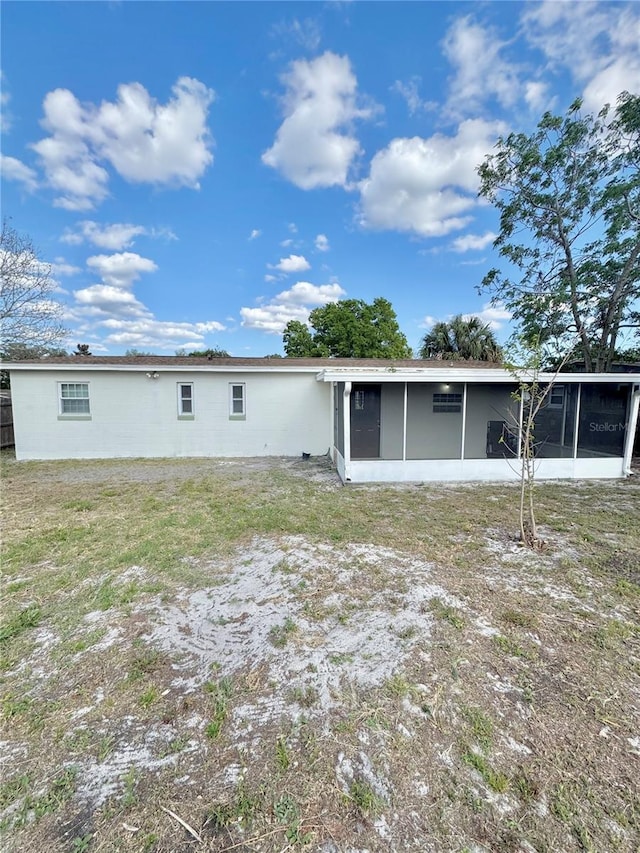 rear view of property featuring a sunroom and a yard