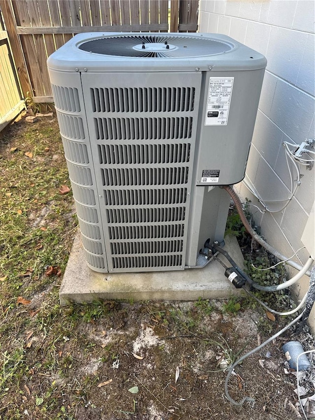 exterior details featuring fence, cooling unit, and concrete block siding