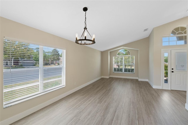 foyer entrance featuring plenty of natural light, light wood finished floors, lofted ceiling, and a chandelier