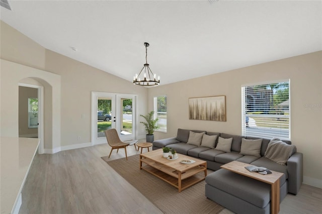 living area with arched walkways, lofted ceiling, french doors, and light wood-style flooring