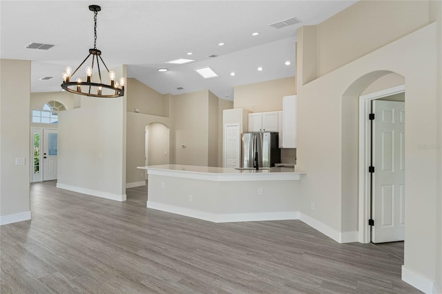 kitchen with freestanding refrigerator, white cabinetry, arched walkways, and high vaulted ceiling