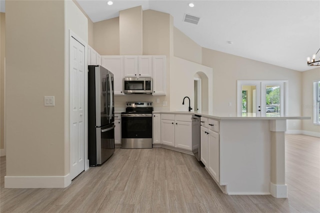 kitchen featuring visible vents, baseboards, light wood finished floors, a peninsula, and stainless steel appliances