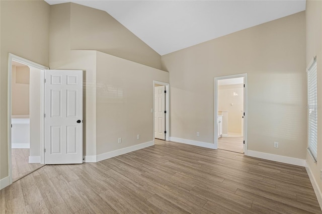 unfurnished bedroom featuring baseboards, high vaulted ceiling, and wood finished floors