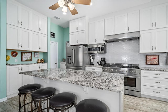 365 N Spaulding Cv, Lake Mary, FL 32746 - kitchen with high quality appliances, under cabinet range hood, a kitchen breakfast bar, ceiling fan, and white cabinets