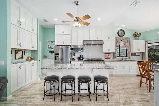 365 N Spaulding Cv, Lake Mary, FL 32746 - kitchen with stainless steel appliances, under cabinet range hood, a sink, decorative backsplash, and a breakfast bar area