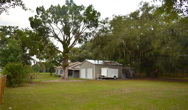 view of yard featuring fence, an outdoor structure, and a garage