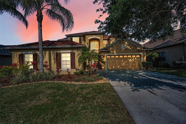 mediterranean / spanish house featuring a garage, driveway, a front lawn, and stucco siding