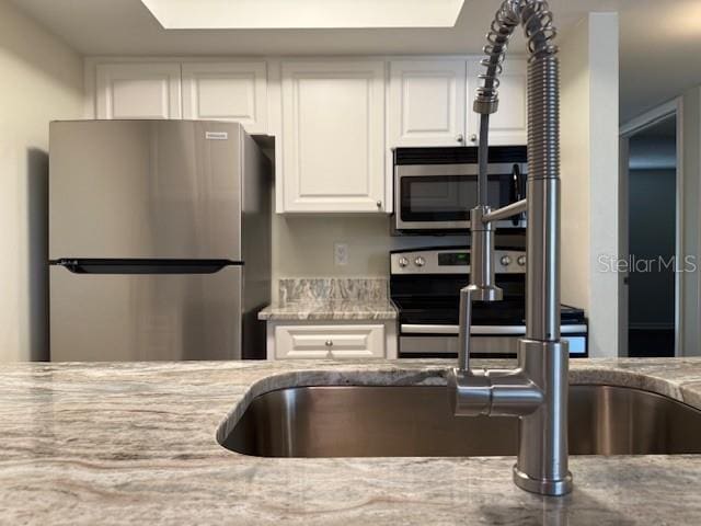 3102 W Horatio St Unit 12, Tampa, FL 33609 - kitchen featuring appliances with stainless steel finishes, white cabinetry, and light stone counters