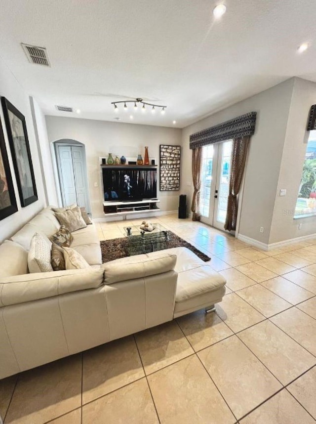 tiled living room with arched walkways, french doors, visible vents, and plenty of natural light