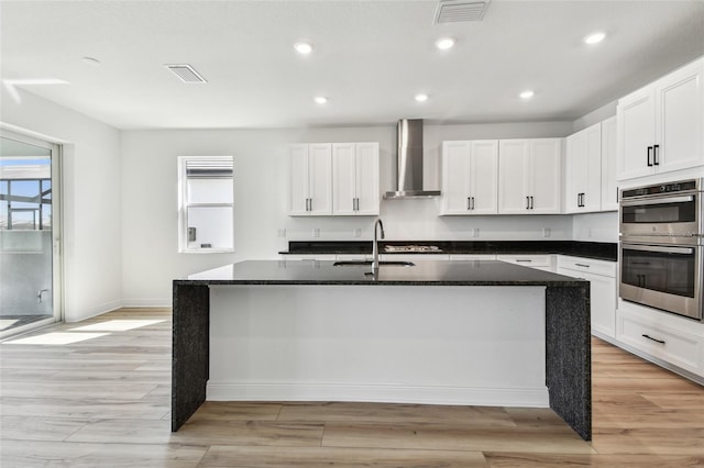 17245 Savory Mist Cir, Bradenton, FL 34211 - kitchen with wall chimney range hood, appliances with stainless steel finishes, a sink, visible vents, and a center island with sink