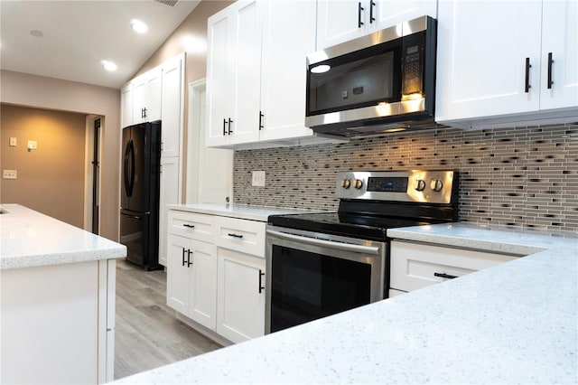 3426 Somerset Ave, Deltona, FL 32738 - kitchen with decorative backsplash, light wood-type flooring, stainless steel appliances, white cabinets, and light stone countertops