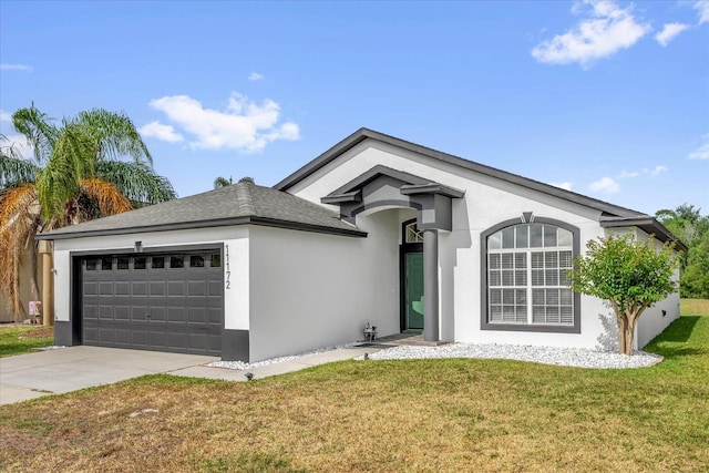 ranch-style home featuring a garage, stucco siding, driveway, and a front yard