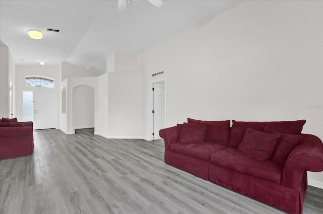 living room with visible vents, a ceiling fan, wood finished floors, arched walkways, and vaulted ceiling